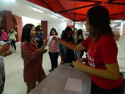 Imagem mostra alunos recebendo camisa da instituição