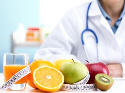 Imagem mostra um médico ao fundo e frutas em cima de uma mesa