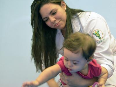 A imagem mostra uma fisioterapeuta com uma criança