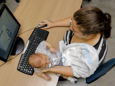 Imagem mostra mãe com bebê em frente ao computador