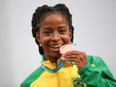 Imagem mostra atleta mordendo a medalha