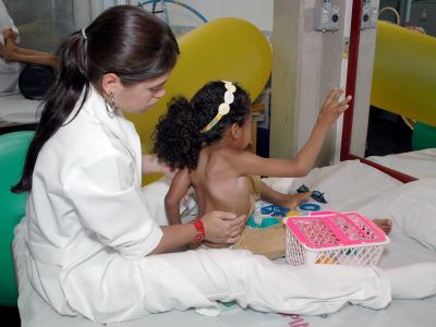 Imagem mostra mulher de jaleco cuidando de criança