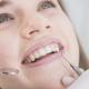 Imagem mostra mulher tendo dentes examinados em dentistas